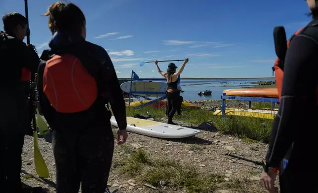 Erin Greene, center, owner of Sup North, demonstrates proper use of a paddle before leading a paddleboarding tour, Thursday, Aug. 8, 2024, in Churchill, Manitoba. (AP Photo/Joshua A. Bickel)