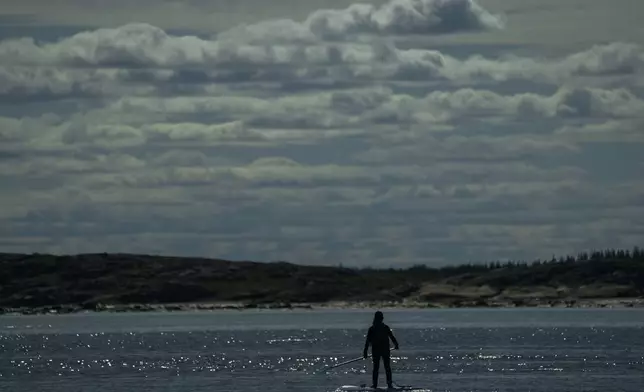 Erin Greene, center, owner of Sup North, stands on her paddleboard in the Churchill River while leading a tour, Thursday, Aug. 8, 2024, in Churchill, Manitoba. (AP Photo/Joshua A. Bickel)