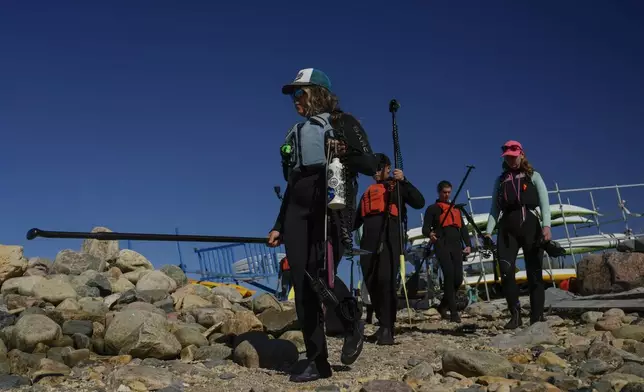 Erin Greene, left, owner of Sup North, leads a tour group down to the shoreline, Thursday, Aug. 8, 2024, in Churchill, Manitoba. (AP Photo/Joshua A. Bickel)