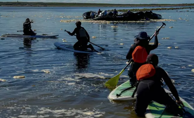 Erin Greene, left, owner of Sup North, directs a person while leading a paddleboarding tour, Thursday, Aug. 8, 2024, in Churchill, Manitoba. (AP Photo/Joshua A. Bickel)