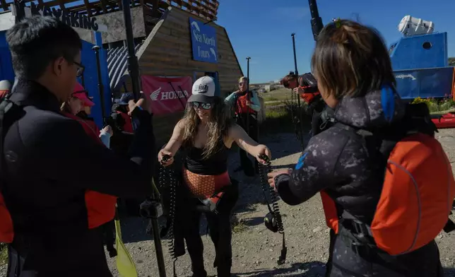 Erin Greene, center, owner of Sup North, hands out equipment before leading a paddleboarding tour, Thursday, Aug. 8, 2024, in Churchill, Manitoba. (AP Photo/Joshua A. Bickel)