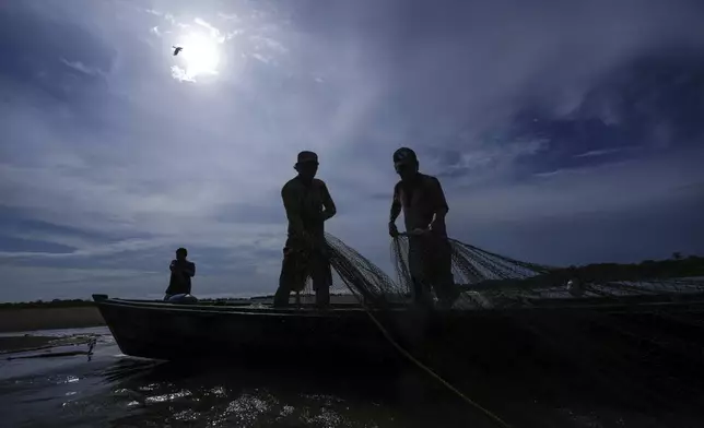 Men look for fish in the Amazon River amid a drought on the outskirts of Leticia, Colombia, Monday, Oct. 21, 2024. (AP Photo/Ivan Valencia)