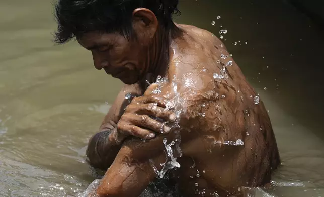 An Indigenous man from the Tikuna community bathes in the Amazon River, in Loma Linda, Colombia, Sunday, Oct. 20, 2024. (AP Photo/Ivan Valencia)