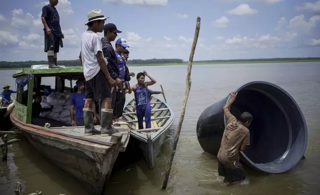 A man from the Tikuna Indigenous community carries a cistern from a nonprofit that can be used to catch and store rainwater for the community amid a drought in Loma Linda, near Leticia, Colombia, Sunday, Oct. 20, 2024. (AP Photo/Ivan Valencia)