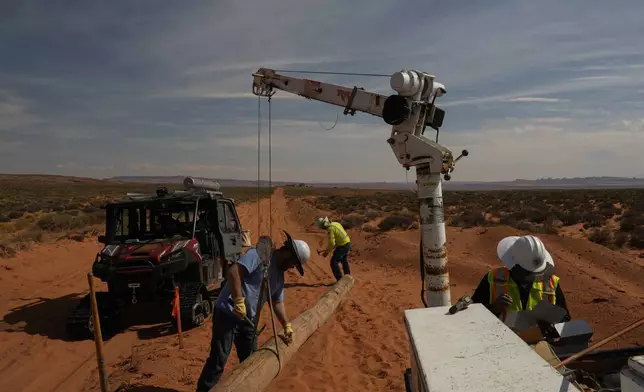 A crew lifts a power line pole during construction at a home, Tuesday, Oct. 8, 2024, on the Navajo Nation in Halchita, Utah. (AP Photo/Joshua A. Bickel)