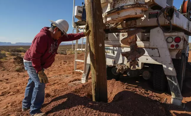 Ryan Smith, left, a foreman with the Navajo Tribal Utility Authority, checks the depth of a power pole during construction, Wednesday, Oct. 9, 2024, on the Navajo Nation in Halchita, Utah. (AP Photo/Joshua A. Bickel)