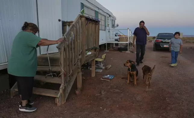 Lorraine Black, left, along with her husband, Ricky Gillis, center, and grandson, Liam Gillis, 7, walk outside their home, Wednesday, Oct. 9, 2024, on the Navajo Nation in Halchita, Utah. (AP Photo/Joshua A. Bickel)