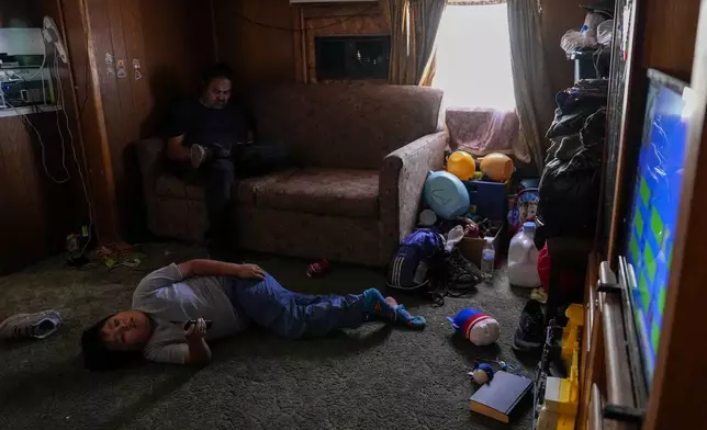 Liam Gillis, 7, relaxes after school with his grandfather, Ricky, top left, Wednesday, Oct. 9, 2024, at their home on the Navajo Nation in Halchita, Utah. (AP Photo/Joshua A. Bickel)