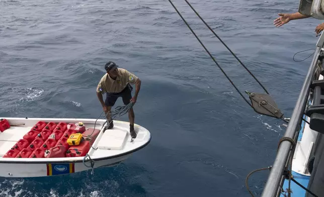 Fred Obak, a Hatohobei State Ranger stationed on Helen Island, Palau, throws a rope to a boat as they prepare to exchange fuel cans on July 17, 2024. (AP Photo/Yannick Peterhans)