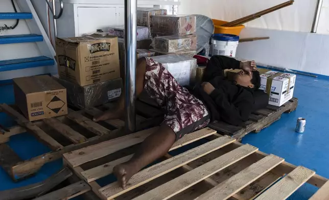 Maxson Blesson sleeps on a wooden pallets on the top deck of the Ryoma, a boat that brings goods through the Pacific Ocean to Helen Island, Palau, on July 15, 2024. (AP Photo/Yannick Peterhans)