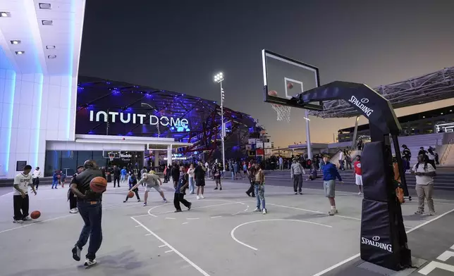 Fans play basketball outside the Intuit Dome, the new home of the Los Angeles Clippers, before the team's NBA preseason basketball game against the Dallas Mavericks Monday, Oct. 14, 2024, in Inglewood, Calif.(AP Photo/Jae C. Hong)