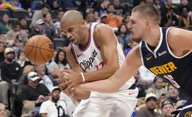 Los Angeles Clippers forward Nicolas Batum (33) and Denver Nuggets center Nikola Jokic (15) reach for a loose ball during the first half of an NBA basketball game Saturday, Oct. 26, 2024, in Denver. (AP Photo/Jack Dempsey)