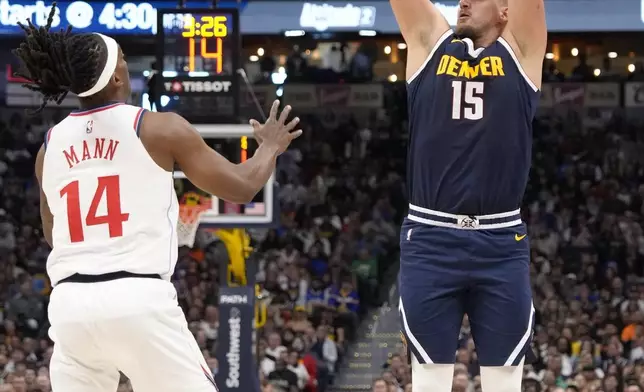 Denver Nuggets center Nikola Jokic (15) shoots a 3-point basket over Los Angeles Clippers guard Terance Mann (14) during the first half of an NBA basketball game Saturday, Oct. 26, 2024, in Denver. (AP Photo/Jack Dempsey)
