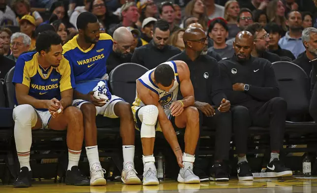 Golden State Warriors' Stephen Curry, center, holds his left ankle after sustaining an injury in the third quarter of an NBA basketball game against the Los Angeles Clippers in San Francisco, Sunday, Oct. 27, 2024. (Jose Carlos Fajardo/Bay Area News Group via AP)