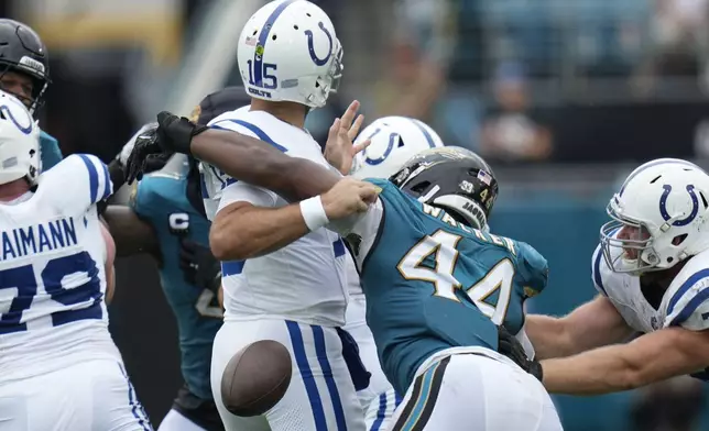 Indianapolis Colts quarterback Joe Flacco (15) fumbles as he is hit by Jacksonville Jaguars' Travon Walker (44) during the first half of an NFL football game, Sunday, Oct. 6, 2024, in Jacksonville, Fla. (AP Photo/John Raoux)