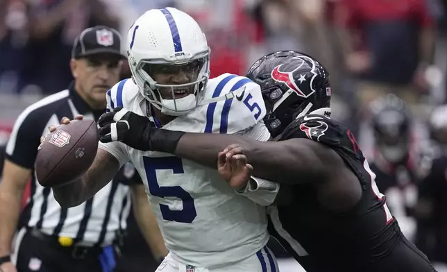 Indianapolis Colts quarterback Anthony Richardson (5) breaks a tackle by Houston Texans defensive tackle Folorunso Fatukasi during the second half of an NFL football game, Sunday, Oct. 27, 2024, in Houston. (AP Photo/Tony Gutierrez)