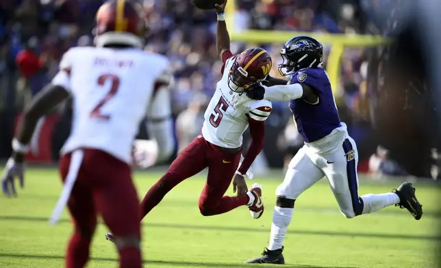 Washington Commanders quarterback Jayden Daniels (5) runs with the ball as Baltimore Ravens inside linebacker Roquan Smith, right, defends during the second half of an NFL football game Sunday, Oct. 13, 2024, in Baltimore. (AP Photo/Nick Wass)