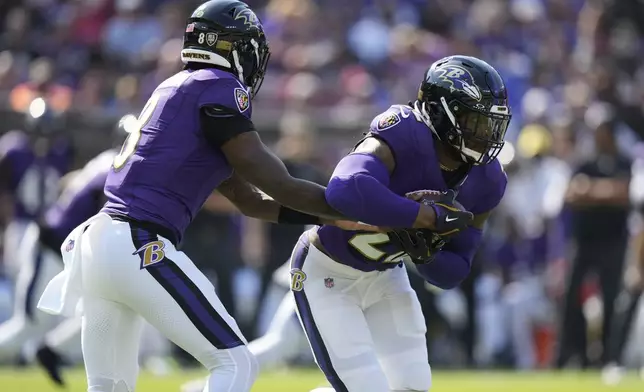 Baltimore Ravens quarterback Lamar Jackson (8) hands off to running back Derrick Henry, right, during the first half of an NFL football game against the Washington Commanders Sunday, Oct. 13, 2024, in Baltimore. (AP Photo/Stephanie Scarbrough)