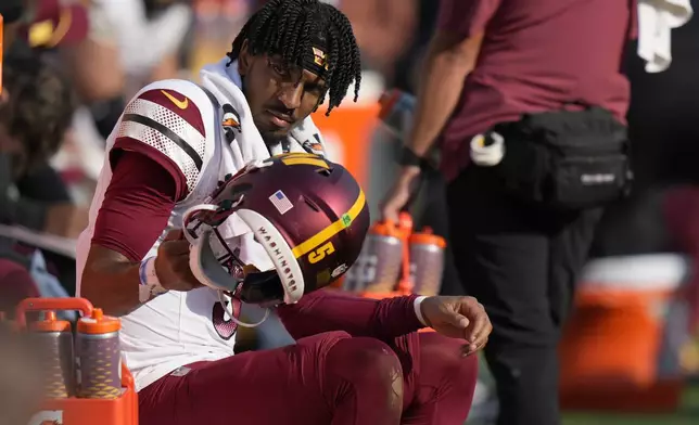 Washington Commanders quarterback Jayden Daniels sits in the bench area during the second half of an NFL football game against the Baltimore Ravens Sunday, Oct. 13, 2024, in Baltimore. (AP Photo/Stephanie Scarbrough)