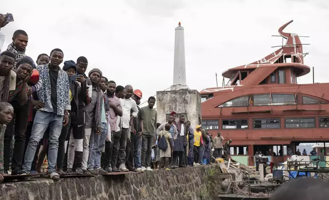 People gather at the port of Goma, Democratic Republic of Congo, after a ferry carrying hundreds capsized on arrival Thursday, Oct. 3, 2024, killing scores. (AP Photo/Moses Sawasawa)