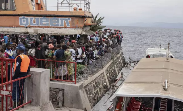 People gather at the port of Goma, Democratic Republic of Congo, after a ferry carrying hundreds capsized on arrival Thursday, Oct. 3, 2024. (AP Photo/Moses Sawasawa)