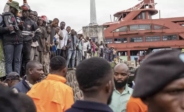 People gather at the port of Goma, Democratic Republic of Congo, after a ferry carrying hundreds capsized on arrival Thursday, Oct. 3, 2024, killing scores. (AP Photo/Moses Sawasawa)