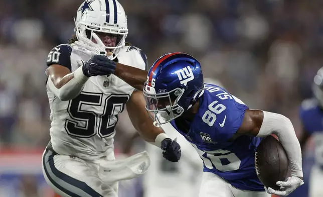 New York Giants wide receiver Darius Slayton (86) stiff arms Dallas Cowboys linebacker Eric Kendricks (50) during the first quarter of an NFL football game, Thursday, Sept. 26, 2024, in East Rutherford, N.J. (AP Photo/Adam Hunger)