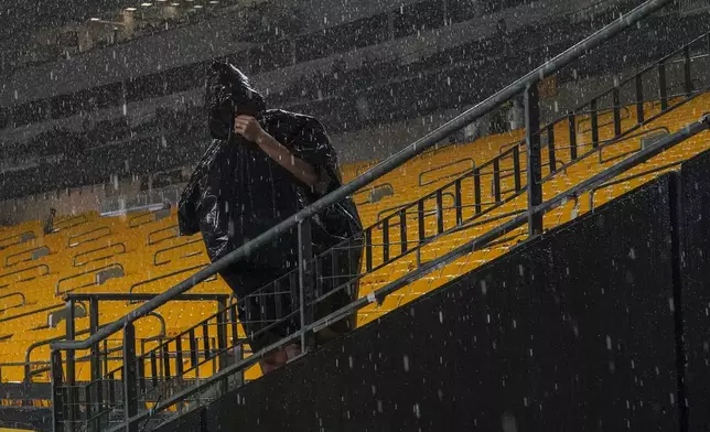 A spectator stands under driving range during a weather delay prior to an NFL football game between the Pittsburgh Steelers and the Dallas Cowboys, Sunday, Oct. 6, 2024, in Pittsburgh. (AP Photo/Matt Freed)