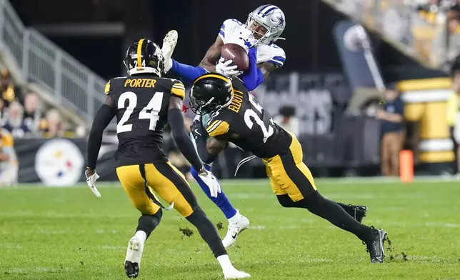 Dallas Cowboys wide receiver Jalen Brooks, top, catches a pass while being hit by Pittsburgh Steelers safety DeShon Elliott (25) during the first half of an NFL football game, Sunday, Oct. 6, 2024, in Pittsburgh. Steelers' Joey Porter Jr. (24) looks on. (AP Photo/Matt Freed)