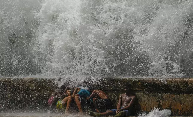 Youths duck behind the Malecon seawall as they play in the surf brought by Hurricane Milton passing through the Gulf of Mexico, in Havana, Cuba, Wednesday, Oct. 9, 2024. (AP Photo/Ramon Espinosa)