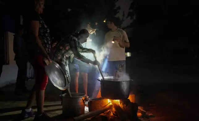 Residents prepare a soup over an open fire during a blackout following the failure of a major power plant in Havana, Cuba, Saturday, Oct. 19, 2024. (AP Photo/Ramon Espinosa)