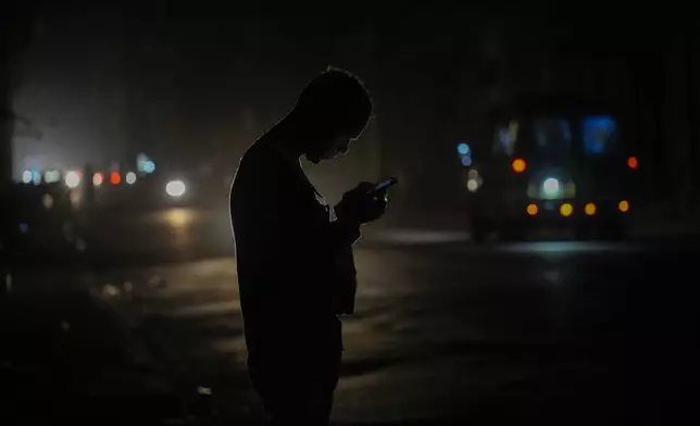 A resident looks at his cell phone on the street during a blackout following the failure of a major power plant in Havana, Cuba, Sunday, Oct. 20, 2024. (AP Photo/Ramon Espinosa)