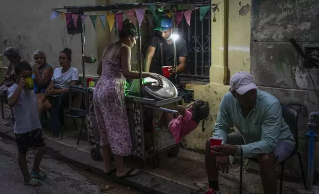 A woman buys soup from a street vendor during a power outage in Havana, Monday, Oct. 21, 2024. (AP Photo/Ramon Espinosa)