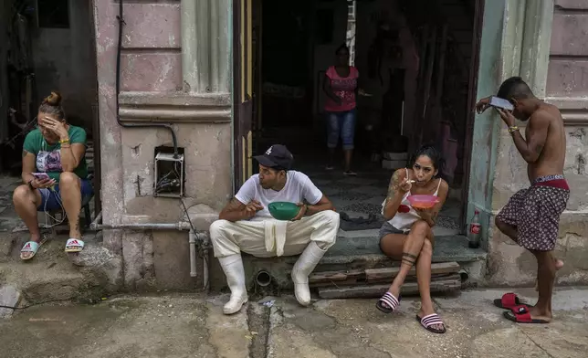 Residents eat outside their homes to avoid the indoor heat during a massive blackout after a major power plant failed in Havana, Cuba, Saturday, Oct. 19, 2024. (AP Photo/Ramon Espinosa)