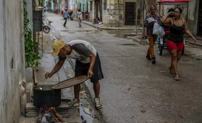 A resident prepares a soup over an open fire during a massive blackout following the failure of a major power plant in Havana, Cuba, Saturday, Oct. 19, 2024. (AP Photo/Ramon Espinosa)