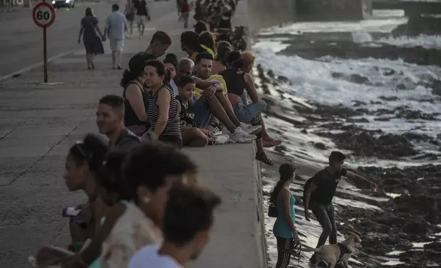 Residents pass the time at the malecon during a blackout following the failure of a major power plant in Havana, Cuba, Sunday, Oct. 20, 2024. (AP Photo/Ramon Espinosa)