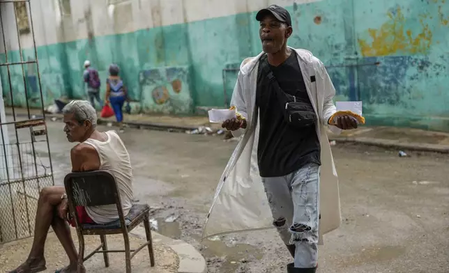A man walks down the street holding slices of pizza during a massive blackout following the failure of a major power plant in Havana, Cuba, Saturday, Oct. 19, 2024. (AP Photo/Ramon Espinosa)
