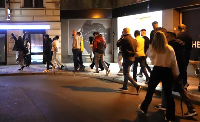 A group of tourists stand in line outside a bar as they attend a pub crawl tour in downtown Prague, Czech Republic, Thursday, Oct. 17, 2024. (AP Photo/Petr David Josek)