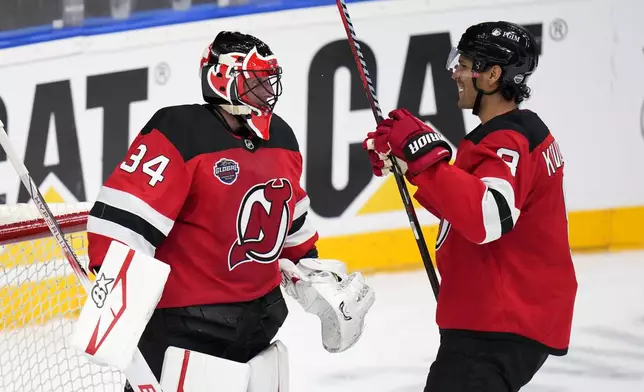 New Jersey Devils' Jake Allen, left, and New Jersey Devils' Johnathan Kovacevic ceelbrate after the NHL hockey game between Buffalo Sabres and New Jersey Devils, in Prague, Czech Republic, Saturday, Oct. 5, 2024. (AP Photo/Petr David Josek)