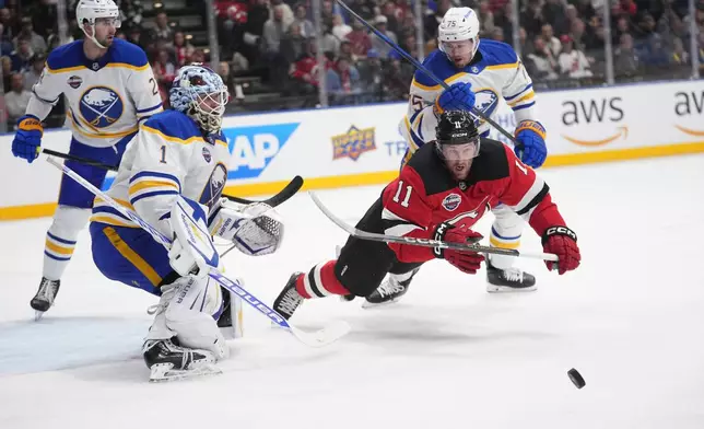 New Jersey Devils' Stefan Noesen, right, and Buffalo Sabres' goaltender Ukko-Pekka Luukkonen battle for the puck during the NHL hockey game between Buffalo Sabres and New Jersey Devils, in Prague, Czech Republic, Friday, Oct. 4, 2024. (AP Photo/Petr David Josek)