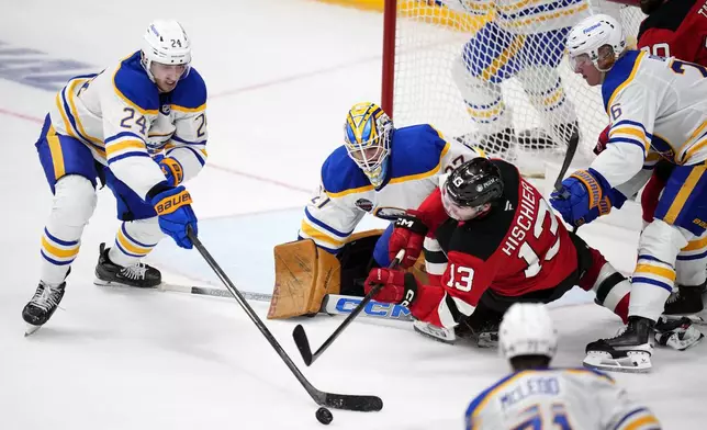 Buffalo Sabres' Dylan Cozen, left, challenges New Jersey Devils' Nico Hischier, 2nd right, during the NHL hockey game between Buffalo Sabres and New Jersey Devils, in Prague, Czech Republic, Saturday, Oct. 5, 2024. (AP Photo/Petr David Josek)