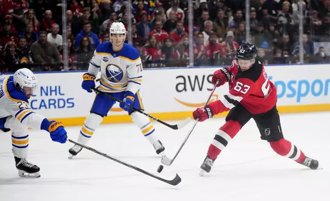 Buffalo Sabres' Mattias Samuelsson, left, trise to block a shot by New Jersey Devils' Jesper Bratt during the NHL hockey game between Buffalo Sabres and New Jersey Devils, in Prague, Czech Republic, Saturday, Oct. 5, 2024. (AP Photo/Petr David Josek)