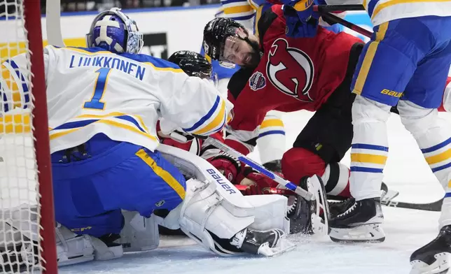 Buffalo Sabres' Ukko-Pekka Luukkonen, left, battles for the puck with New Jersey Devils' Tomas Tatar, second from right, during the NHL hockey game between Buffalo Sabres and New Jersey Devils, in Prague, Czech Republic, Friday, Oct. 4, 2024. (AP Photo/Petr David Josek)