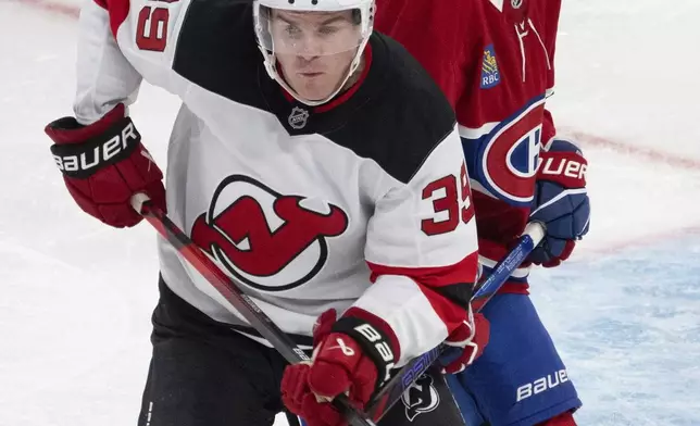 Montreal Canadiens defenseman David Reinbacher (64) battles for position with New Jersey Devils Mike Hartman (39) during the thrid period of a preseason NHL hockey game in Montreal, Tuesday, Sept. 24, 2024. (Ryan Remiorz/The Canadian Press via AP)