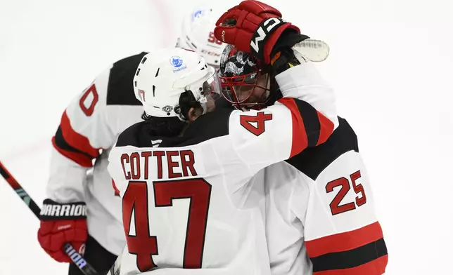 New Jersey Devils center Paul Cotter (47) celebrates with goaltender Jacob Markstrom (25) after an NHL hockey game against the Washington Capitals, Saturday, Oct. 12, 2024, in Washington. The Devils won 5-3. (AP Photo/Nick Wass)