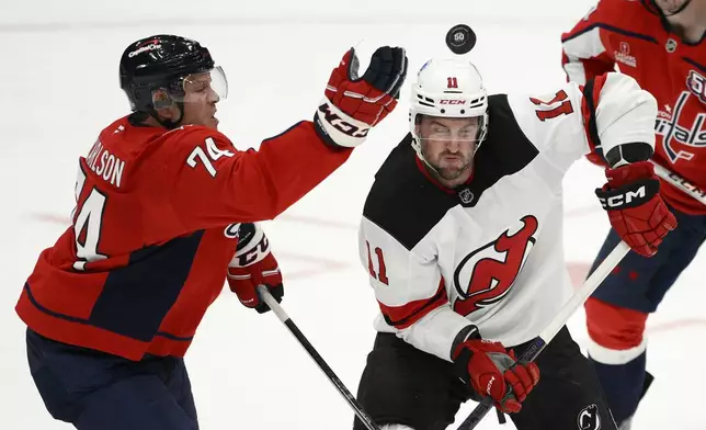 Washington Capitals defenseman John Carlson (74) reaches for the puck against New Jersey Devils right wing Stefan Noesen (11) during the third period of an NHL hockey game, Saturday, Oct. 12, 2024, in Washington. The Devils won 5-3. (AP Photo/Nick Wass)