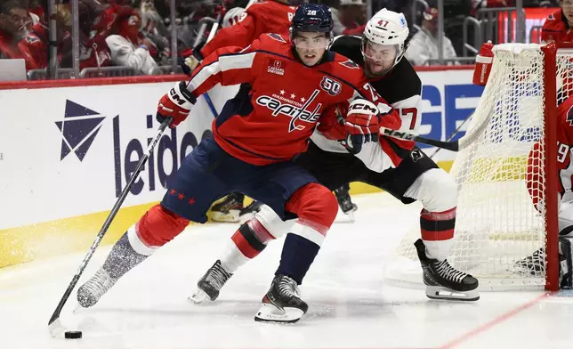 Washington Capitals center Hendrix Lapierre (29) and New Jersey Devils center Paul Cotter (47) battle for the puck during the second period of an NHL hockey game, Saturday, Oct. 12, 2024, in Washington. (AP Photo/Nick Wass)