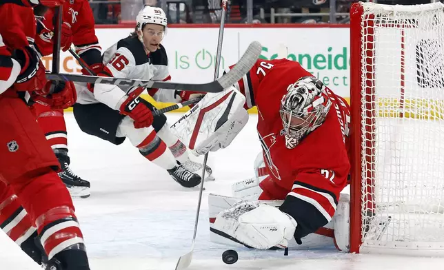 Carolina Hurricanes goaltender Pyotr Kochetkov (52) freezes the puck in front of New Jersey Devils' Erik Haula (56) during the first period of an NHL hockey game in Raleigh, N.C., Tuesday, Oct. 15, 2024. (AP Photo/Karl B DeBlaker)