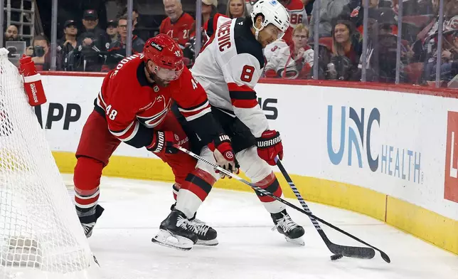 New Jersey Devils' Johnathan Kovacevic (8) battles with Carolina Hurricanes' Jordan Martinook (48) for the puck during the second period of an NHL hockey game in Raleigh, N.C., Tuesday, Oct. 15, 2024. (AP Photo/Karl B DeBlaker)