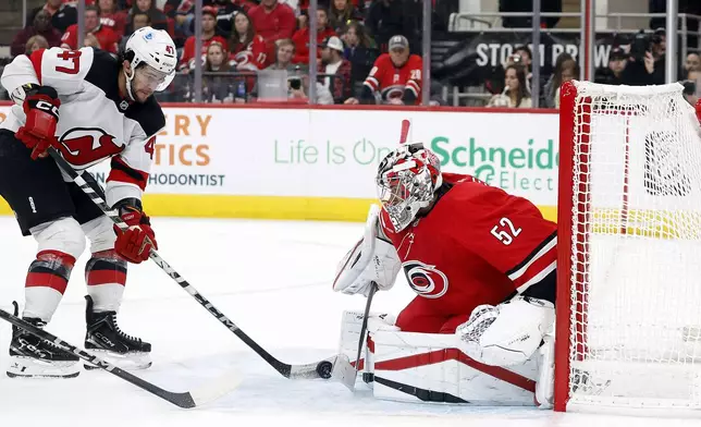 Carolina Hurricanes goaltender Pyotr Kochetkov (52) blocks the shot of New Jersey Devils' Paul Cotter (47) during the third period of an NHL hockey game in Raleigh, N.C., Tuesday, Oct. 15, 2024. (AP Photo/Karl B DeBlaker)